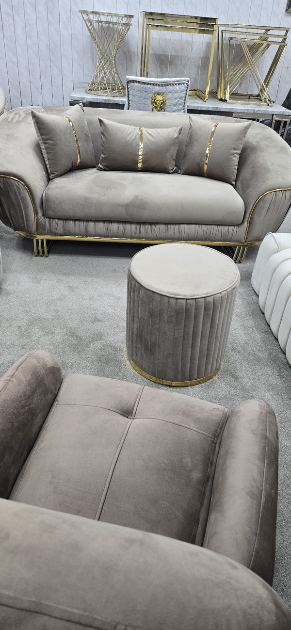 Beige sofa with decorative pillows and a matching ottoman in a room setting.