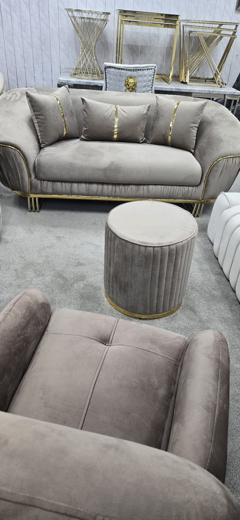 Beige sofa with decorative pillows and a matching ottoman in a room setting.