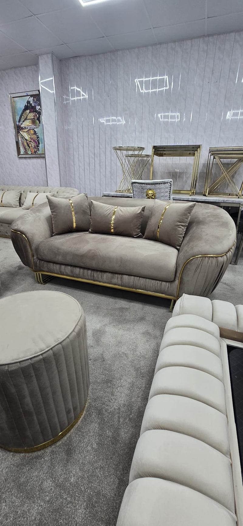 Beige sofa with gold accents in a room with grey walls and a rug.