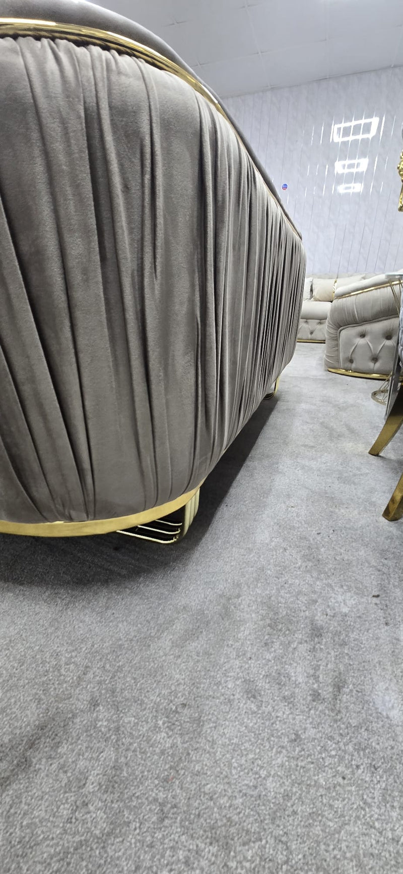 Beige upholstered chair with gold accents in a showroom setting