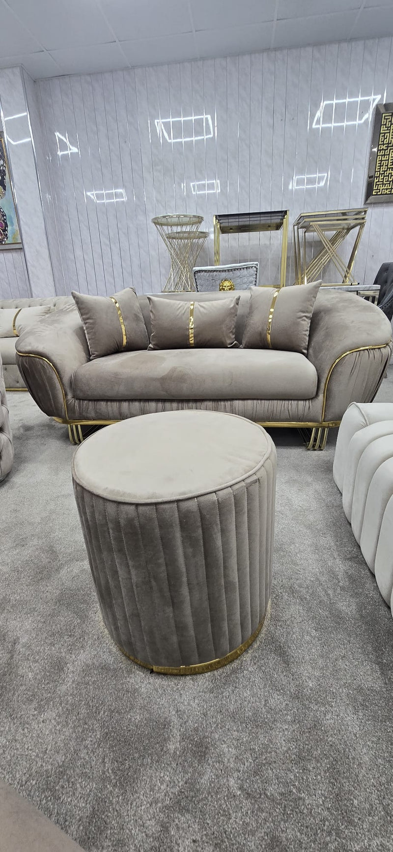 Beige velvet sofa and matching ottoman in a room with light grey walls and carpet.